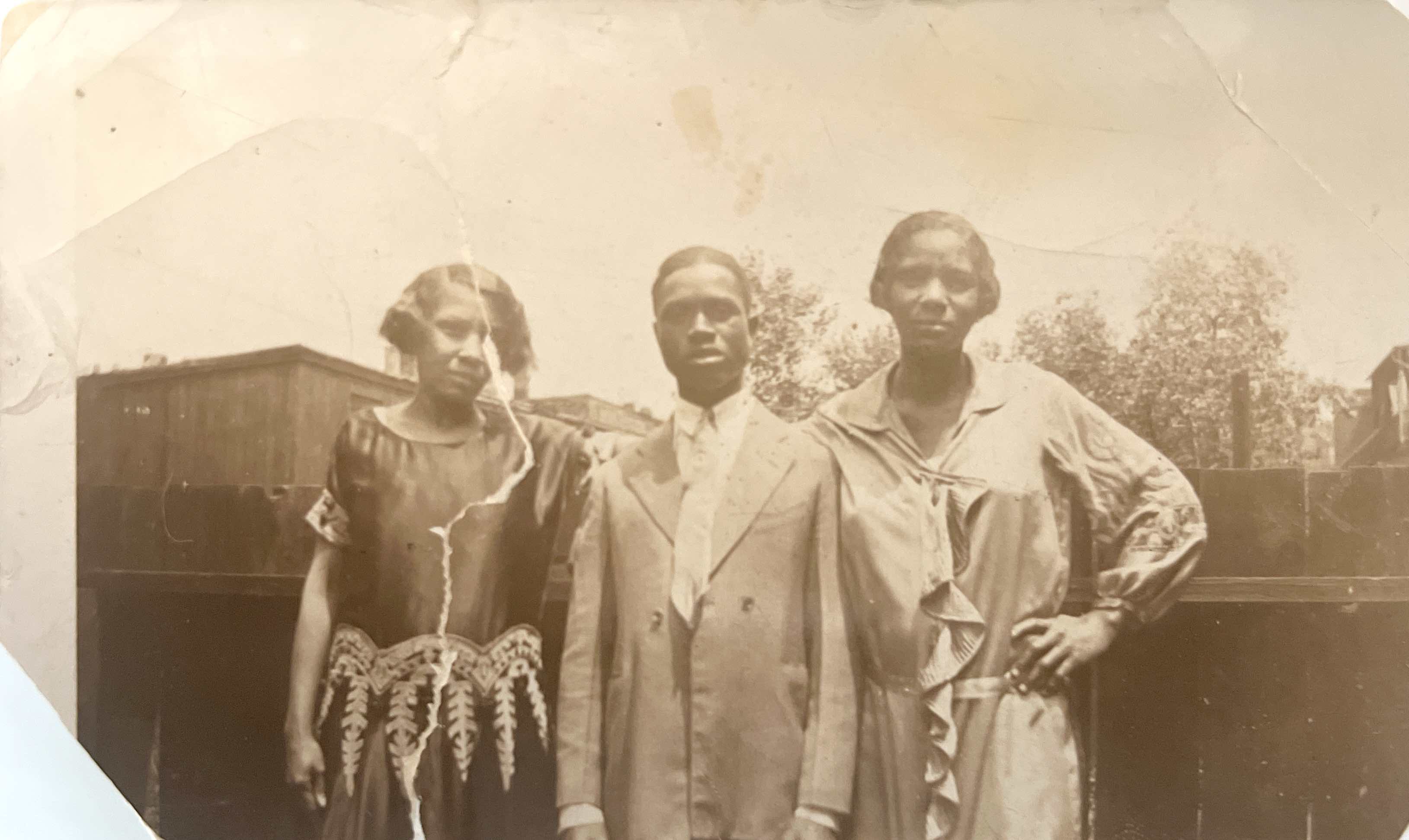 Three people in vintage clothing standing together outdoors